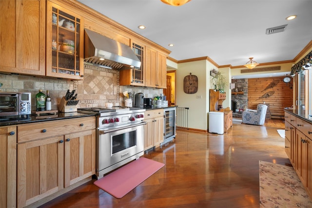 kitchen with tasteful backsplash, beverage cooler, designer range, crown molding, and wall chimney range hood