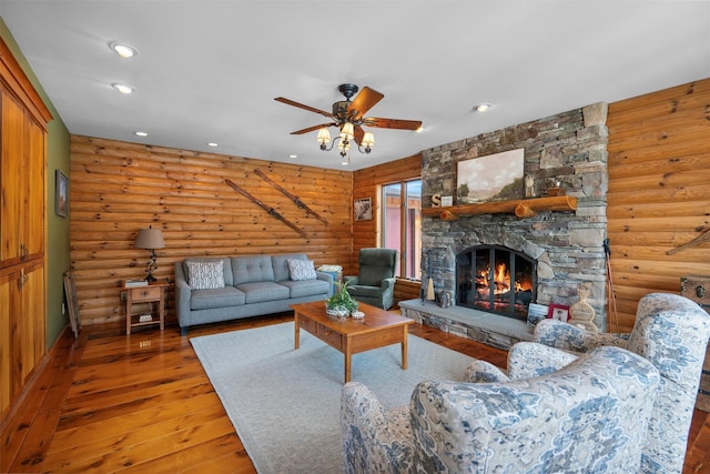 living room featuring hardwood / wood-style flooring, ceiling fan, a stone fireplace, and log walls