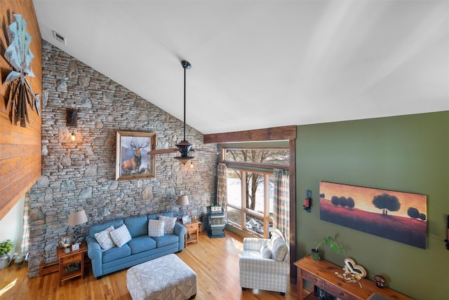 living room featuring high vaulted ceiling, light hardwood / wood-style floors, ceiling fan, and a wood stove