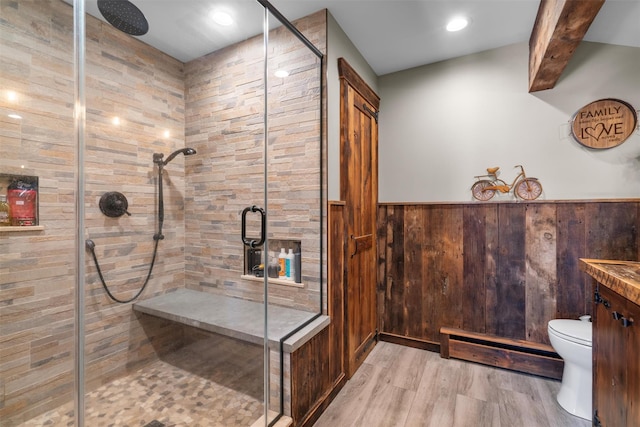 bathroom featuring wood-type flooring, a shower with shower door, toilet, and wood walls