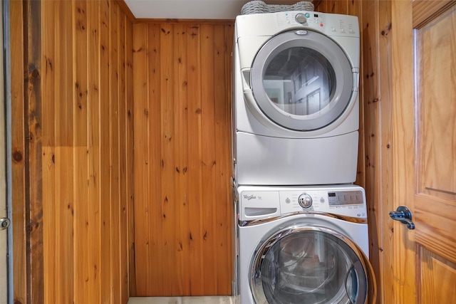 washroom featuring stacked washer and clothes dryer and wood walls