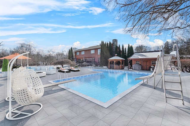 view of pool featuring a patio area, an outdoor structure, a diving board, and a water slide