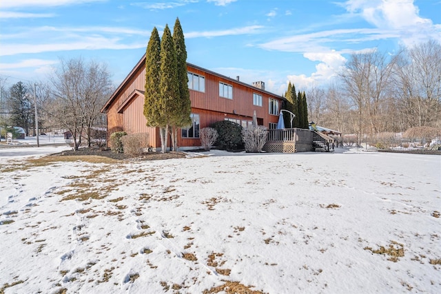 snow covered rear of property featuring a deck