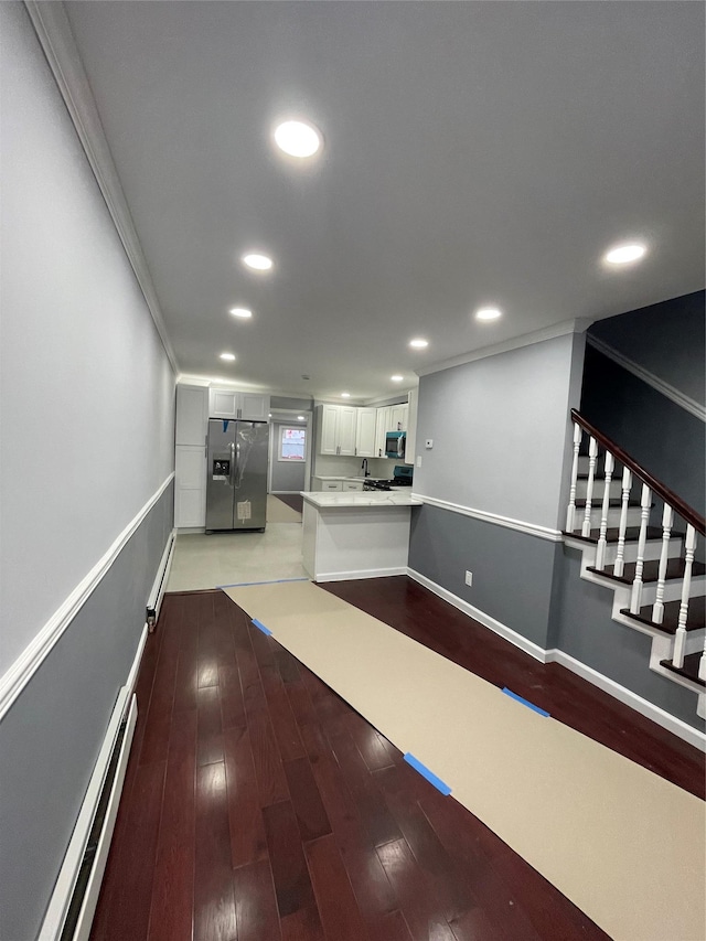 kitchen with appliances with stainless steel finishes, light wood-type flooring, white cabinets, and baseboard heating