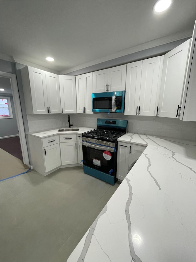 kitchen with white cabinets, light stone countertops, sink, and stainless steel gas stove