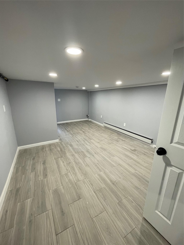 basement featuring light wood-type flooring and baseboard heating