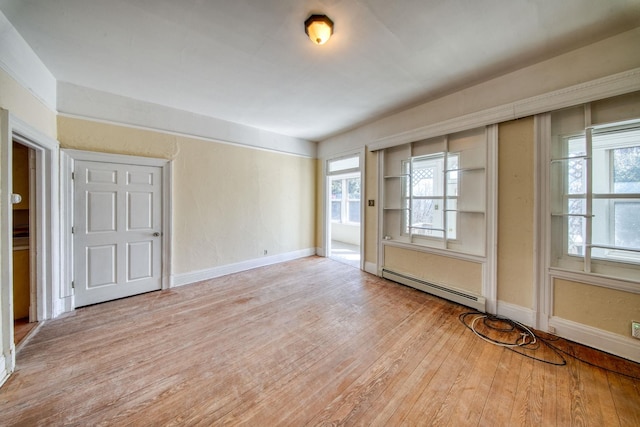 spare room with a baseboard radiator, wood-type flooring, and baseboards