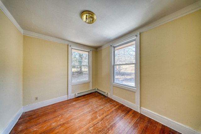 empty room featuring baseboard heating, hardwood / wood-style flooring, and baseboards