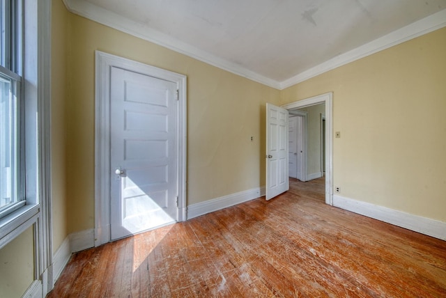 spare room featuring hardwood / wood-style flooring, baseboards, and crown molding