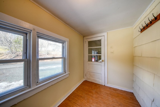 unfurnished room with ornamental molding, light wood-type flooring, and baseboards