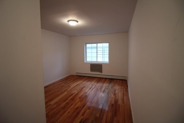 unfurnished room featuring a baseboard heating unit and dark wood-type flooring