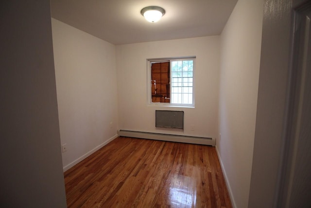 unfurnished room featuring a baseboard radiator and hardwood / wood-style floors