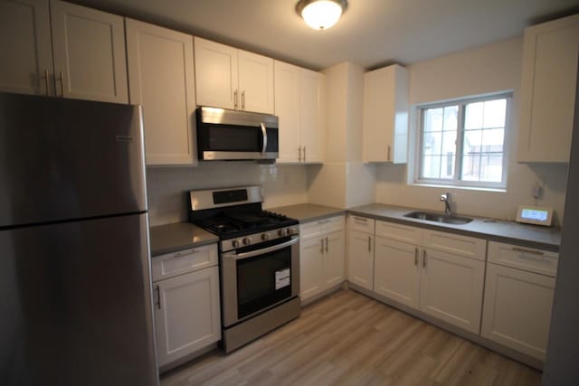 kitchen with white cabinetry, appliances with stainless steel finishes, sink, and light hardwood / wood-style flooring