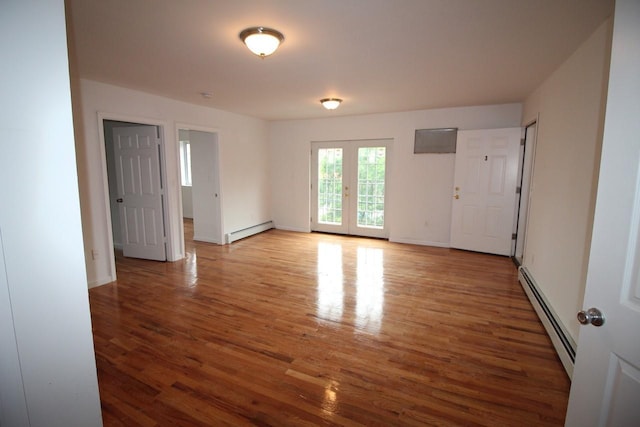 spare room with baseboard heating, french doors, and hardwood / wood-style flooring