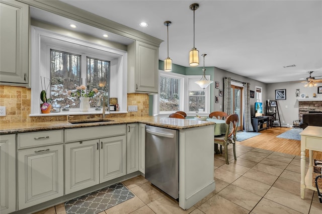 kitchen featuring decorative light fixtures, sink, stainless steel dishwasher, light stone counters, and a barn door