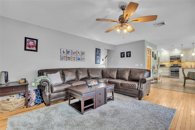 living room with ceiling fan and light wood-type flooring