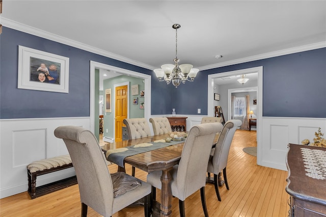 dining area featuring crown molding, a chandelier, and light wood-type flooring