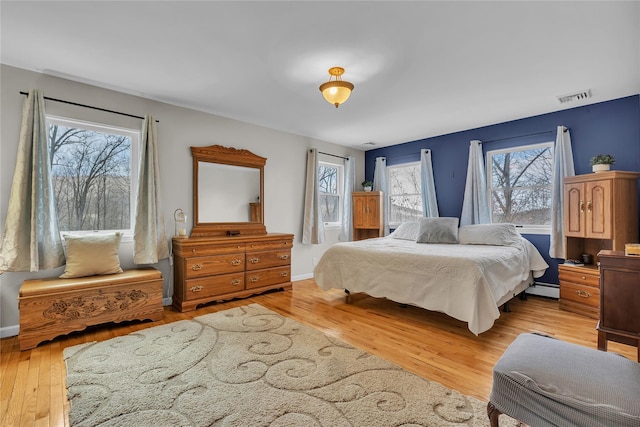 bedroom with a baseboard heating unit and light wood-type flooring