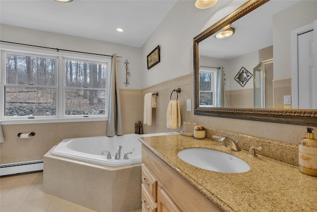 bathroom with tile walls, tiled bath, vanity, a baseboard heating unit, and tile patterned floors