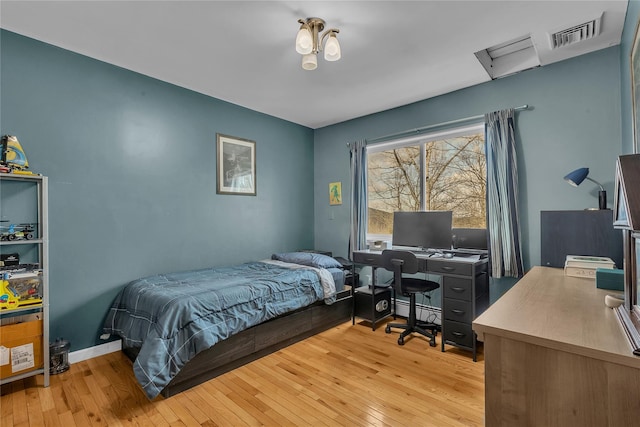 bedroom featuring a baseboard heating unit and light wood-type flooring