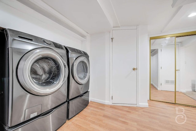 laundry area featuring washing machine and clothes dryer and light wood-type flooring