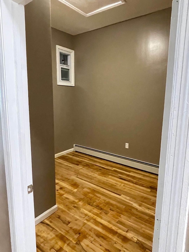 unfurnished room featuring wood-type flooring and baseboard heating