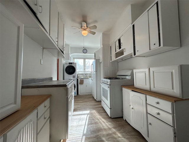 kitchen featuring stacked washer / dryer, white cabinetry, ceiling fan, and white appliances