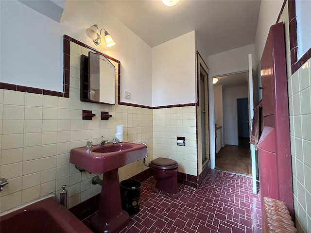 bathroom featuring radiator heating unit, tile walls, a bathtub, and toilet