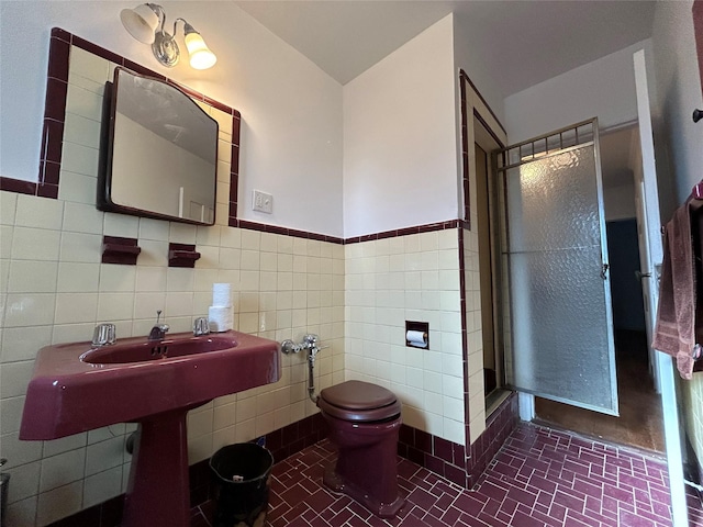 bathroom featuring toilet, an enclosed shower, tile patterned flooring, and tile walls