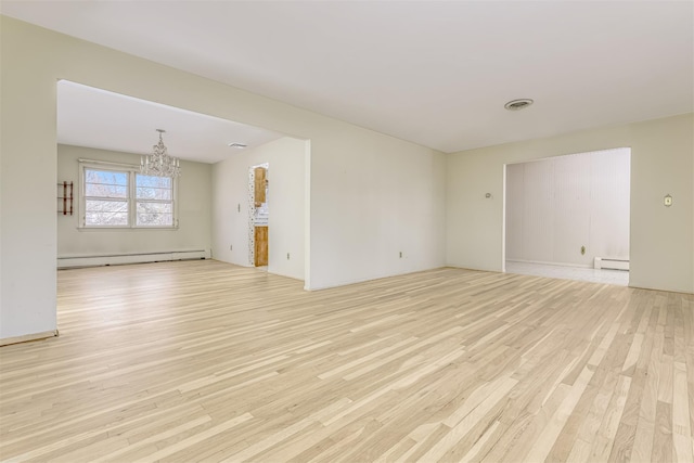 unfurnished room featuring baseboard heating, light hardwood / wood-style flooring, and a notable chandelier