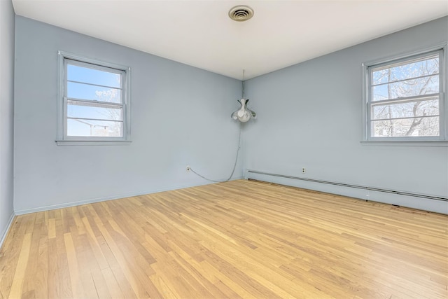 unfurnished room featuring a baseboard heating unit and light hardwood / wood-style flooring