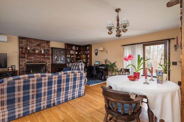 dining room featuring a fireplace, a chandelier, light hardwood / wood-style floors, and an AC wall unit