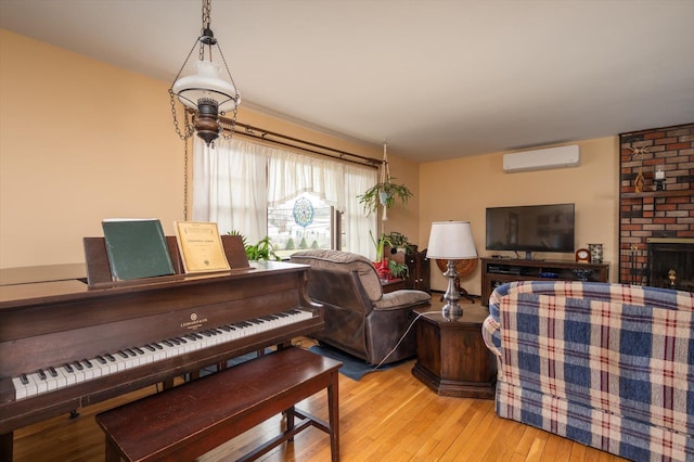 misc room featuring a fireplace, a wall unit AC, and light hardwood / wood-style flooring