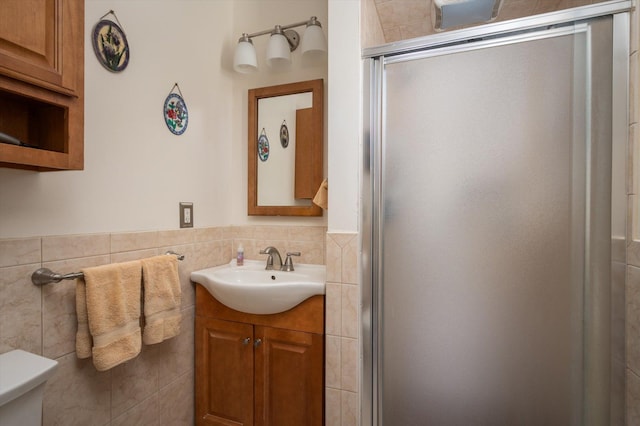 bathroom featuring walk in shower, vanity, toilet, and tile walls