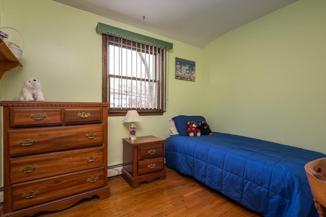 bedroom featuring a baseboard radiator, lofted ceiling, and light wood-type flooring