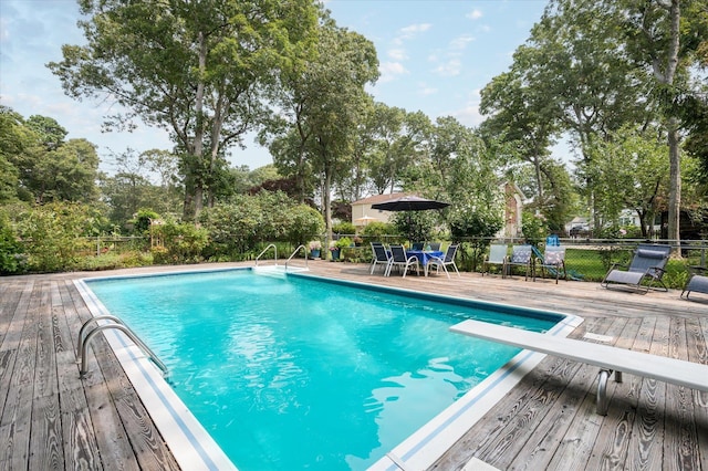 view of swimming pool featuring a wooden deck and a diving board