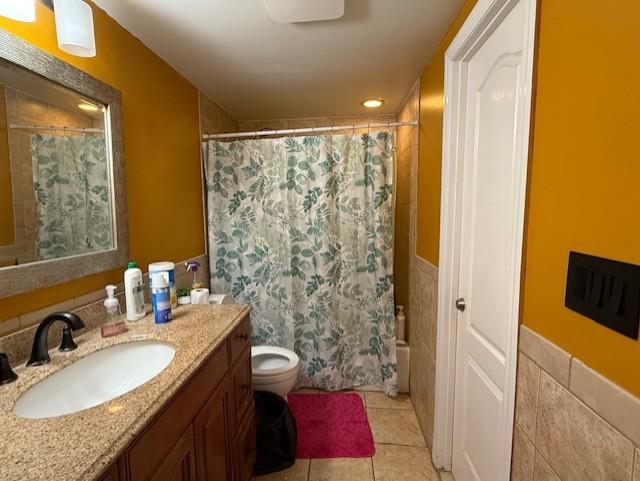 full bathroom featuring tile walls, tile patterned flooring, vanity, shower / bath combination with curtain, and toilet