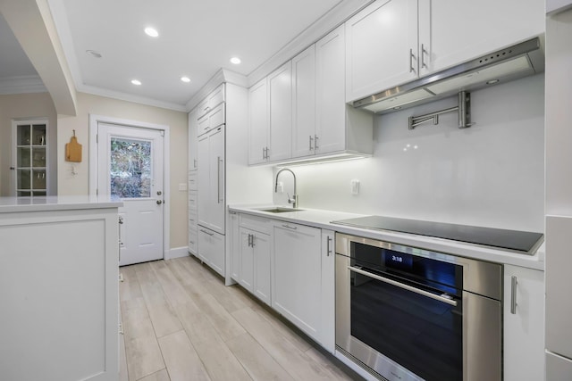 kitchen with sink, black electric cooktop, ornamental molding, oven, and white cabinets