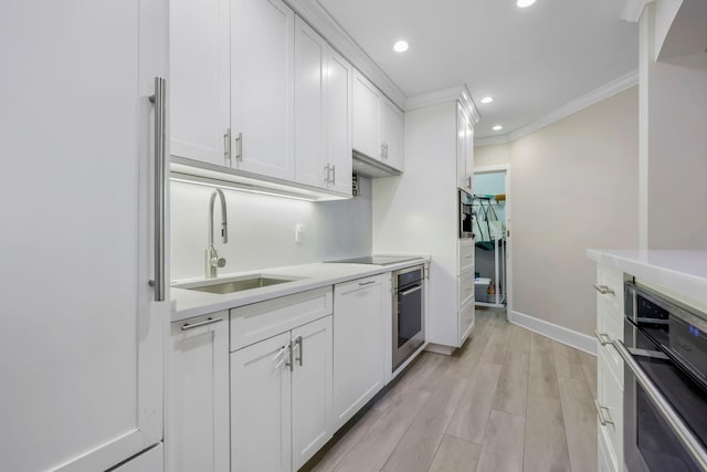 kitchen with sink, white cabinetry, stainless steel oven, refrigerator, and ornamental molding