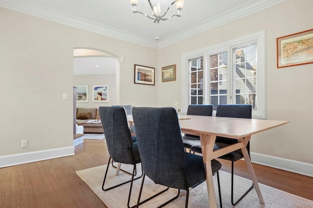 dining area with ornamental molding, a chandelier, and light wood-type flooring