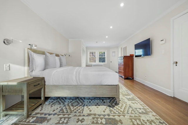 bedroom with ornamental molding and light hardwood / wood-style floors