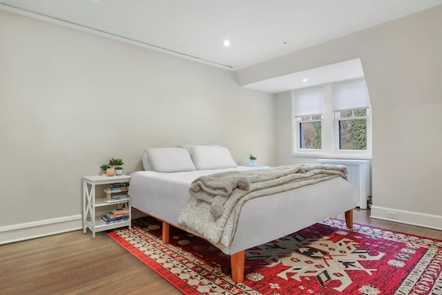 bedroom with radiator heating unit and hardwood / wood-style floors