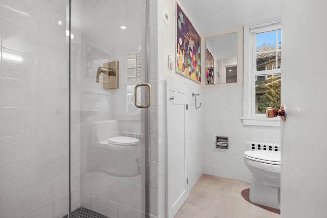 bathroom with toilet, an enclosed shower, tile patterned flooring, and tile walls