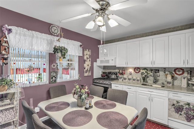 kitchen with white cabinetry, white appliances, light stone countertops, and sink