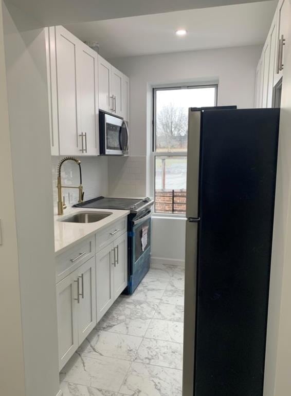 kitchen with white cabinetry, appliances with stainless steel finishes, sink, and backsplash