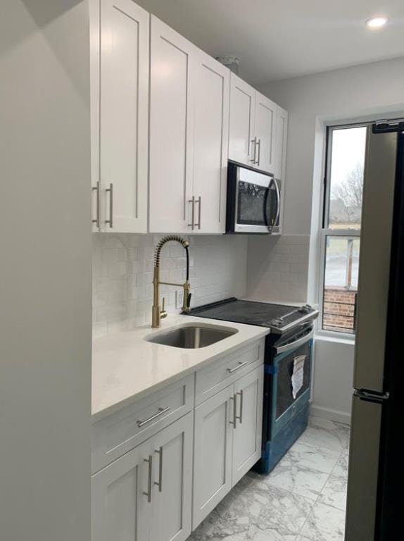 kitchen featuring appliances with stainless steel finishes, sink, white cabinets, and backsplash