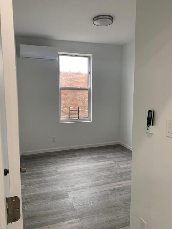 spare room with a wall mounted air conditioner and wood-type flooring