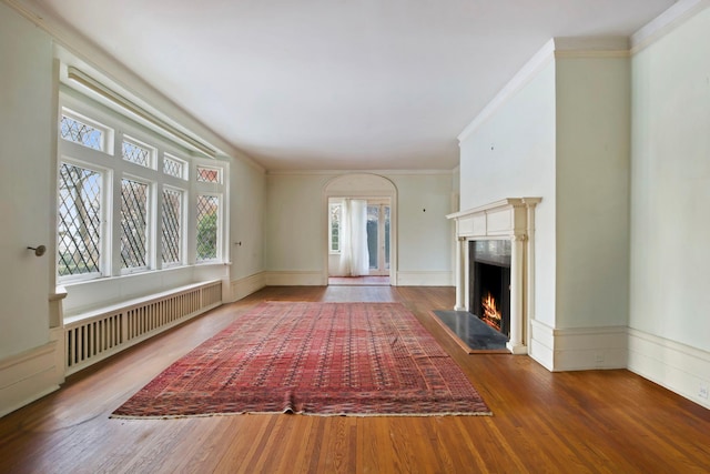 unfurnished living room with hardwood / wood-style flooring, ornamental molding, radiator heating unit, and a high end fireplace