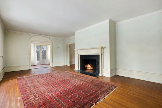 unfurnished living room featuring dark hardwood / wood-style flooring, ornamental molding, a premium fireplace, and french doors