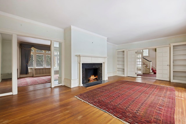 unfurnished living room featuring hardwood / wood-style flooring, ornamental molding, and a high end fireplace